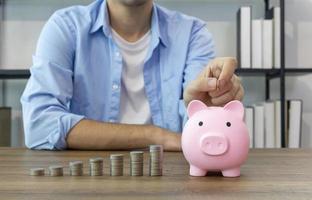 Hand of people putting coin in his piggy bank with stack of growing coin for saving and investment concept photo