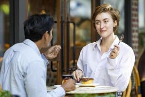 Caucasian couple have a date at european style cafe bistro enjoying morning vibe around the city square with sweet pastry and a cup of coffee photo