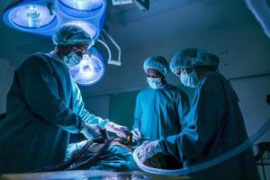 equipo de médicos cirujanos que usan desfibrilador para dar una descarga eléctrica al corazón del paciente que sufre un paro cardíaco en la sala de cirugía de emergencia por concepto de atención médica foto