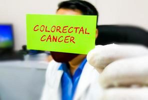 término médico de cáncer colorrectal en una tarjeta en la mano del médico. concepto médico y de salud. foto