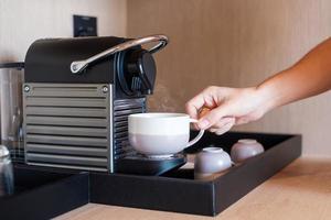 Hand making Espresso by Coffee Machine with capsules on wood table photo