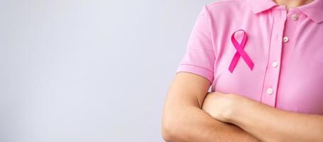 mes de concientización sobre el cáncer de mama de octubre rosa, la mano de la mujer sostiene una cinta rosa y usa una camisa para apoyar la vida y la enfermedad de las personas. concepto del mes nacional de los sobrevivientes del cáncer, la madre y el día mundial del cáncer foto