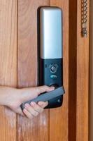 man holding handle of smart digital door lock while open or close the door. Technology, electrical and lifestyle concepts photo