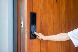 man holding handle of smart digital door lock while open or close the door. Technology, electrical and lifestyle concepts photo