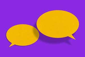 Speech balloon shaped yellow paper against purple background. photo