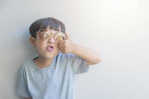 retrato de un joven feliz de origen asiático con un pantalones gris y gafas de sol mira la cámara foto