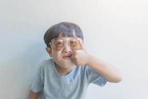 Portrait of a happy young boy of Asia origin in a gray shirt and sunglasses look at the camera photo