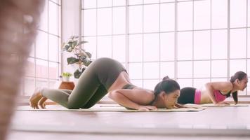 dos chicas asiáticas haciendo ejercicios de yoga en casa.