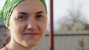 detailopname portret van een Kaukasisch vrouw op zoek Bij de camera en lachend. mooi jong vrouw zonder bedenken in een groen zon hoed Aan een zonnig zomer dag buitenshuis. zonnestraal. video