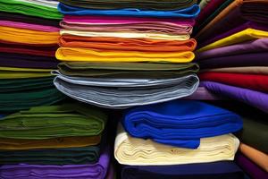 Variedad artística colores de tonos de sombra telas apiladas en el estante de la tienda minorista para la venta foto