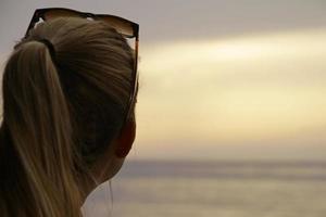 Blonde woman seen from the back looking at the horizon photo