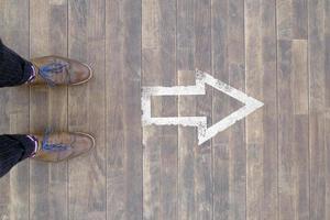 The way forward - Man standing in front of an arrow sign on the floor photo