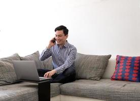 hombre trabajando desde casa con una laptop en la sala de estar foto