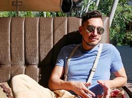 Man wearing sunglasses and suspenders in a cafe on a sunny day photo