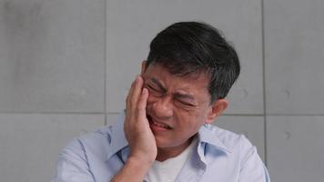 Asian senior man suffering from toothache. photo