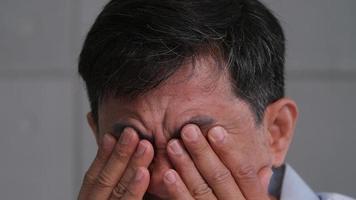 Asian old man was rubbing his eyes, tired of staring for a long time. photo