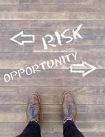 Top view on a man standing in front of the words Risk and Opportunity with arrows pointing to the left and right side of the picture photo