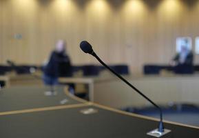 sala de conferencias con paredes de madera y micrófonos en cada asiento foto