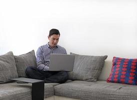 hombre trabajando desde casa con una laptop en la sala de estar foto