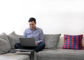 hombre trabajando desde casa con una laptop en la sala de estar foto