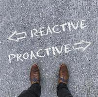 Man looking down at the words REACTIVE and PROACTIVE written on the floor photo