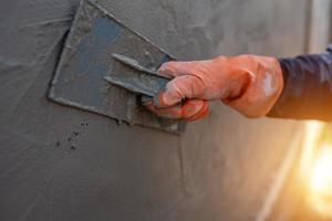 Close-up shot of a cement worker using a trowel to plaster the walls