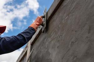 trabajador de enlucido enlucido de cemento en el sitio de construcción. foto