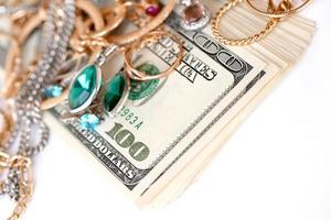 Many expensive golden and silver jewerly rings, earrings and necklaces with big amount of US dollar bills on white background. Pawnshop or jewerly shop photo