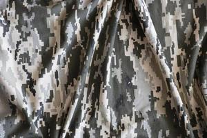 Fabric with texture of Ukrainian military pixeled camouflage. Cloth with camo pattern in grey, brown and green pixel shapes. Official uniform of Ukrainian soldiers photo