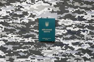 Ukrainian military ID on fabric with texture of pixeled camouflage. Cloth with camo pattern in grey, brown and green pixel shapes with Ukrainian army personal token photo