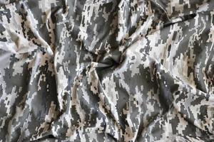 Fabric with texture of Ukrainian military pixeled camouflage. Cloth with camo pattern in grey, brown and green pixel shapes. Official uniform of Ukrainian soldiers photo