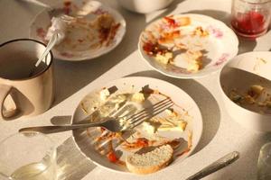 platos sucios vacíos con cucharas y tenedores en la mesa después de la comida. concepto de final de banquete. platos sin lavar foto