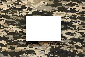 Fabric with texture of Ukrainian military pixeled camouflage and white blank paper. Cloth with camo pattern in grey, brown and green pixel shapes. photo