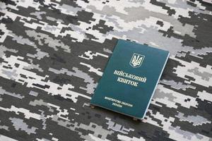 Ukrainian military ID on fabric with texture of pixeled camouflage. Cloth with camo pattern in grey, brown and green pixel shapes with Ukrainian army personal token photo