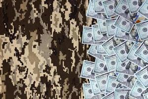 US dollar bills on fabric with texture of Ukrainian military pixeled camouflage. Cloth with camo pattern in grey, brown and green pixel shapes photo