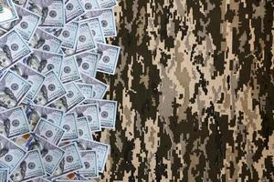 US dollar bills on fabric with texture of Ukrainian military pixeled camouflage. Cloth with camo pattern in grey, brown and green pixel shapes photo