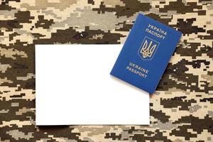 Ukrainian foreign passport on fabric with texture of military pixeled camouflage. Cloth with camo pattern in grey, brown and green pixel shapes and Ukrainian ID photo