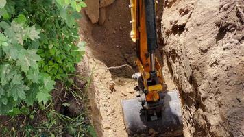 creuser un trou dans le sol avec une pelle. l'attention est concentrée sur le godet de l'excavatrice enlevant une partie du sol. video