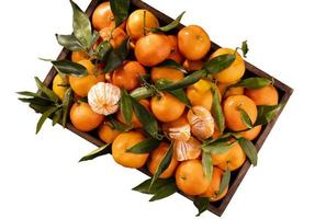 Fresh mandarin oranges fruit or tangerines with leaves in wooden box, top view photo