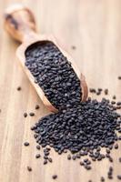 Bio natural black sesame seeds on wooden spoon. photo