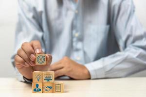 business strategy Action plan Goal and target icons with hand stack a wood cube block on a table. Copy space company development startup concept. photo