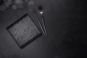 Empty square black plate on dark moody background with copy space photo