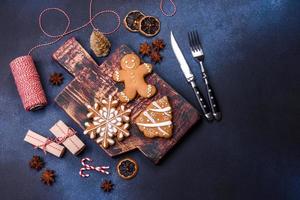 elementos de decoración navideña, dulces y pan de jengibre en una tabla para cortar madera foto