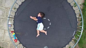 1 anno vecchio bambino ragazzo è in posa sotto il di droni telecamera su un' trampolino nel il giardino video