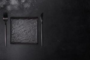 Empty square black plate on dark moody background with copy space photo