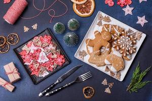 adornos navideños y panes de jengibre en una mesa de hormigón oscuro. preparándose para la celebración foto