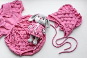 Beautiful baby knitted clothes and a toy for a newborn baby photo