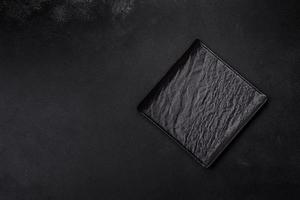 Empty square black plate on dark moody background with copy space photo