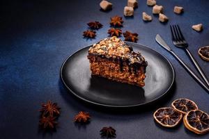 un trozo de delicioso pastel fresco con nueces y chocolate en un plato negro sobre un fondo azul oscuro foto