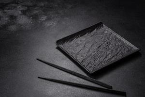 Empty square black plate on dark moody background with copy space photo